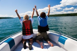 Two kids in the bow of a motorboat acting out a scene from the movie "Titanic".